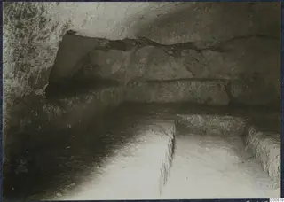 Interior of a rock-cut chamber at Vouni, with cut ledges along the walls and a stepped floor