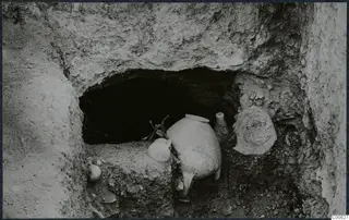 Pottery vessels in front of a rock-cut tomb opening during excavation at Vouni