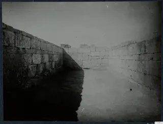 Ashlar stone walls of a narrow passage or room at Vouni, with a paved or cleared floor between them.