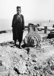 Charalampos, who owned the land, standing beside a sculpted limestone head at Vouni
