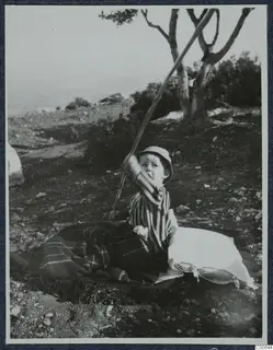 Stefan Gjerstad, a young child, sitting on a blanket outside the house at Vouni, holding a long stick.