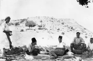Five people resting outdoors at Vouni, including Einar Gjerstad and Alfred Westholm, with a bare hill behind them.