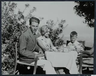 Probably Alfred Westholm and Gudrun Atterman at breakfast outdoors at Vouni, with a boy at a laid table.