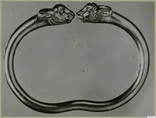Gold bracelet with two animal heads, facing each other across the open ends of the band.