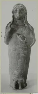 Standing terracotta figurine with arms bent up toward the chest and a band-patterned headdress, against a grey background
