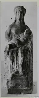Terracotta figurine of an adult holding a child in their arms, shown frontally against a plain background