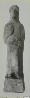 Standing human figurine with arms bent across the body, on a rectangular base, from Vouni