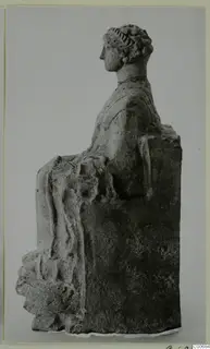 Seated figure in profile, with hair bound up in a band and draped garment over the lap, on a rectangular block seat.