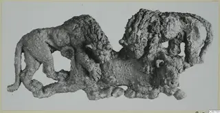 Corroded bronze relief of two lions attacking a bull, photographed flat against a pale background.