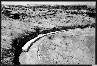 Curved row of pale cut stone blocks exposed in an excavation at Soli, the theatre