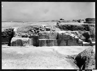 Excavated large stone blocks in courses at the theatre at Soli, with rubble heaped behind and sea on the horizon