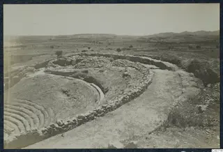 The theatre at Soli: curved stone tiers and walls in the foreground, a flat plain and hills beyond