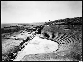 The theatre at Soli seen from above, with curved stone seating tiers, a level central floor and the sea beyond.