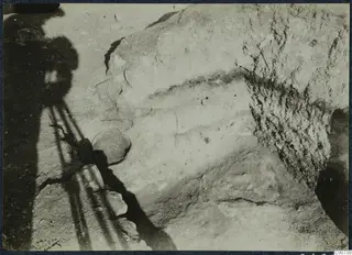 Excavation at Vouni palace: a layered earth face on the right, with a rounded vessel and stones in shadow on the left.