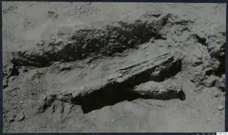Excavated trench at Vouni with a long stone block partly uncovered in the soil.