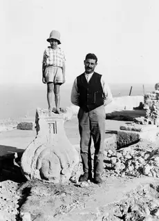 Boy standing on top of a carved limestone sculpture at Vouni, with a man in a waistcoat beside it.
