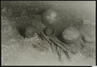 Tomb 306 c. at Lapithos during excavation, with a skeleton and pottery vessels on the tomb chamber floor
