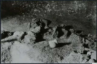 Tomb 11 at Milia: excavated tomb chamber floor with skeletal bones and small vessels in place