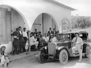 Group of men and a child outside a whitewashed arched building, with a Volvo car in front in Pyrgos