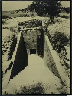 Dromos leading down steps to the entrance of T.1 at Trachonas, flanked by cut stone walls.