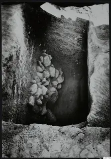 Excavation trench at Plakes, Lapithos, with a heap of stones set against one wall.