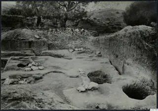 Excavation at Plakes, Lapithos, showing cut rock surfaces, small pits and a row of stones.
