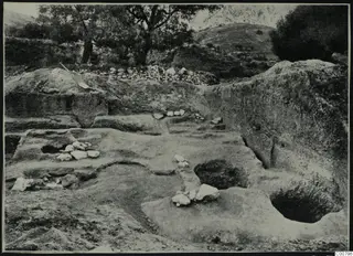 Excavation at Plakes, Lapithos, with a spade leaning at the edge of the cutting and trees behind.