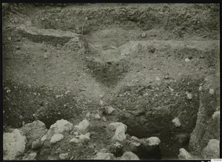 Excavation trench at Plakes, Lapithos, with layered soil faces and pale stones at the bottom