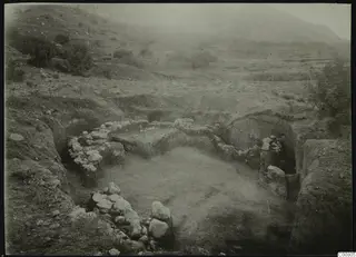 Excavation at Plakes, Lapithos, with exposed stone walls, cut banks of soil and trees in the background.