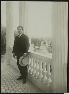 Perikles Kaplanis, mayor of Lapithos, standing with a straw hat on a columned balcony above the town