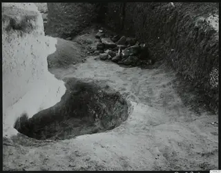 Excavation at Plakes, Lapithos, with a pit and a heap of stones against an earth section