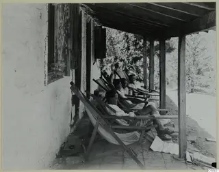 Four people resting in deckchairs on the veranda of a whitewashed building at Machairas