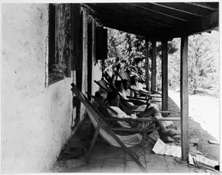 Four people resting in deckchairs on a veranda at Machairas.