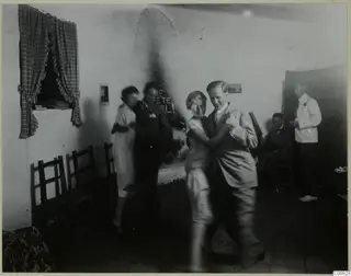 Dancing couples in a whitewashed room at Machairas, with one pair blurred in motion.