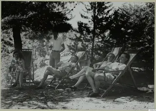 People resting in deckchairs under pine trees at Machairas.