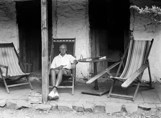 John Lindros seated in a deck chair on a veranda at Machairas, holding a pipe.