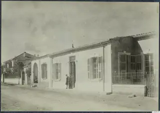 The Swedish Institute in Nicosia, a long white single-storey building with shuttered windows, with two people at its doorway.