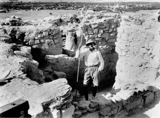Erik Sjöqvist standing with a long pole among excavated walls at Idalion