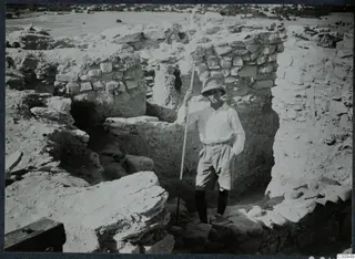 Erik Sjöqvist standing by the west wall at Idalion, holding a long pole among excavated stone walls.