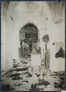 Interior of the monastery church at Lambousa, with leafy branches scattered over the stone floor and an icon screen at the far end