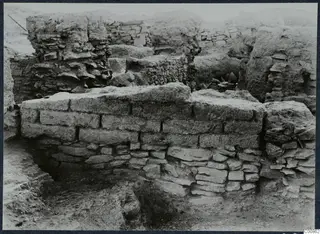 Excavated wall of stone and mud brick at the Idalion acropolis, with rubble and ruined walls behind it.
