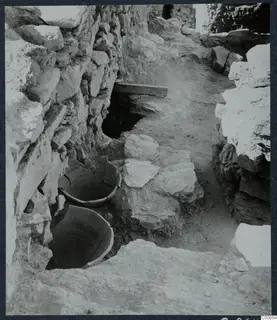 Excavation at Idalion Acropolis with two large vessels sunk into the ground beside a rough stone wall