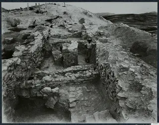 Stone walls in L 8 at Idalion, with a man standing between them in the excavation