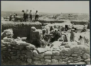 Workers excavating stone and mud-brick walls at F7, Idalion, with a wheelbarrow and spades