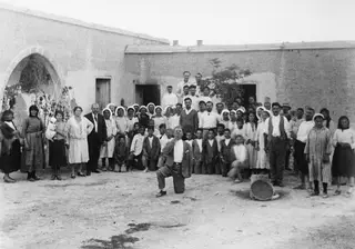 Group photograph of a farewell party in a dusty courtyard at Idalion, with a whitewashed building behind