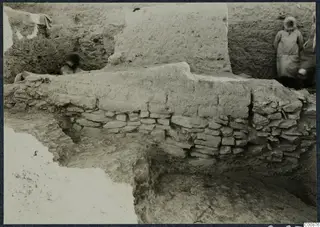 Excavation at Idalion Acropolis: a thick earthen brick wall rests on a low course of flat stones in a trench