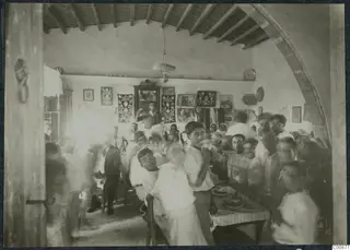 Farewell party in a vaulted room at Idalion, with people crowded around a table laid with food