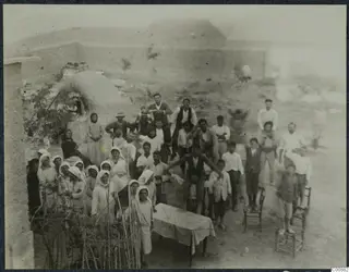Farewell party of a crowd of people gathered in a dusty yard at Panajiotis, Idalion.