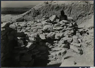 Excavation at Idalion Acropolis with rough stone walls and a person standing behind them.