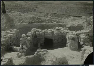 Excavated stone walls at Idalion Acropolis, with a standing person on the edge of the excavation at upper left.